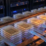 Stacked memory modules interwoven with copper power busbars and liquid-cooling tubes in a dark data center hall
