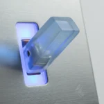 A translucent toggle switch mounted in a brushed-metal panel, caught mid-flip under cool studio light