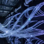 Fiber-optic strands and glowing blue data streams converging into a dark data-center aisle, representing web data infrastructure.