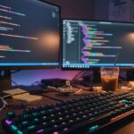 A developer desk at night with dual monitors glowing with abstract code syntax colors