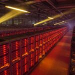 Rows of server racks glowing red and orange under dramatic industrial lighting